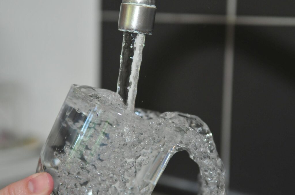 Pahar cu apă la robinet, apă clară după filtrare